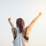 woman wearing black bra and white tank top raising both hands on top